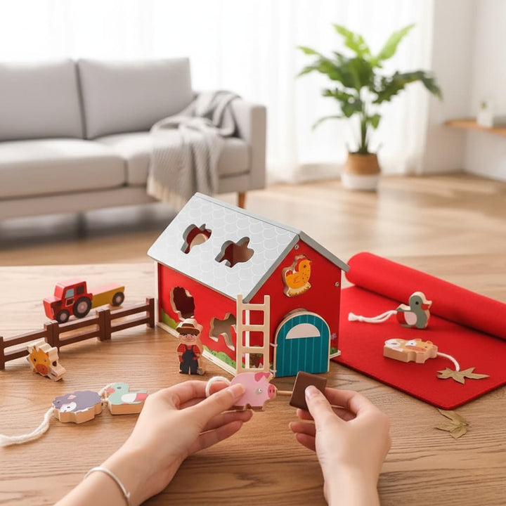 Children's hands playing with a wooden farm toy set on a wooden floor.