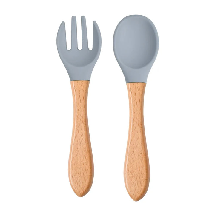 A set of green silicone spoon and fork with wooden handles designed for babies and toddlers.
