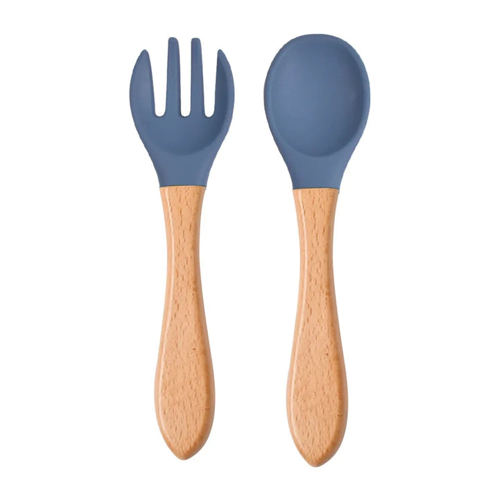 A set of green silicone spoon and fork with wooden handles designed for babies and toddlers.