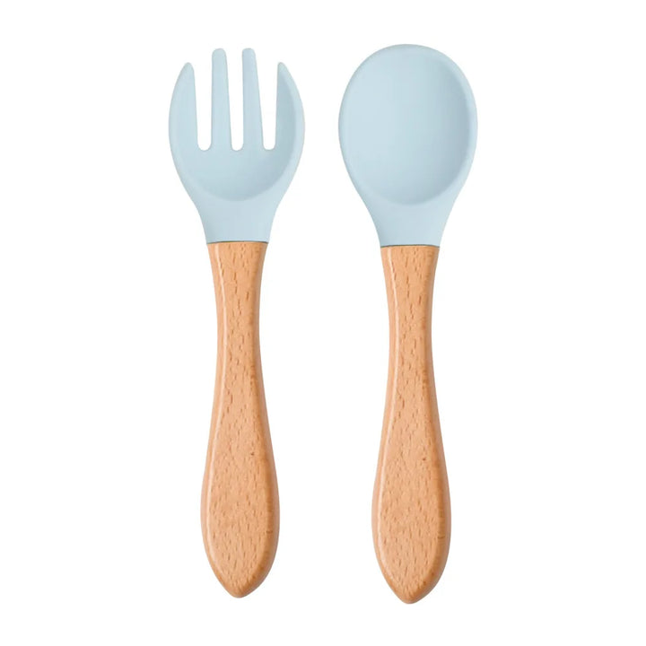 A set of green silicone spoon and fork with wooden handles designed for babies and toddlers.