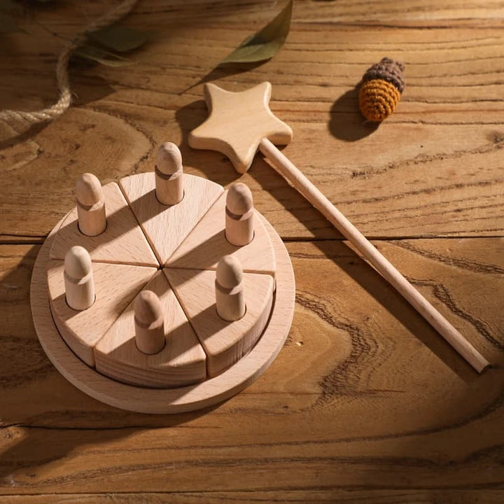 Wooden toy set on a wooden surface with a star-shaped wand and acorn.